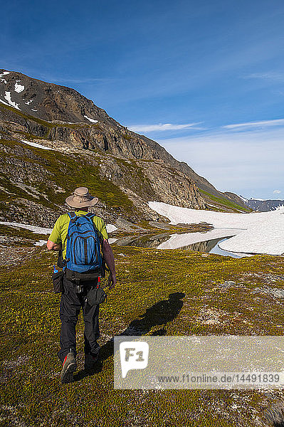 Ein Mann wandert neben einem Teich in der Nähe des Harding-Eisfeldes im Kenai Fjords National Park auf der Kenai-Halbinsel in Süd-Zentral-Alaska.