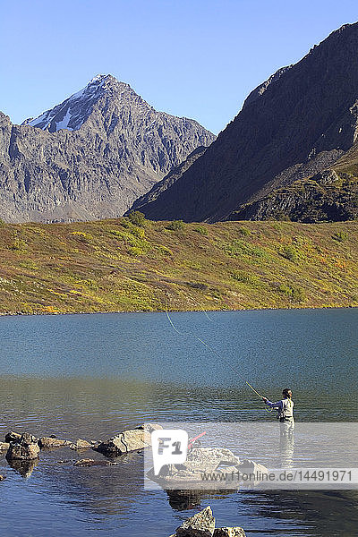Flyfisherwoman casting in middle of Symphony Lake Chugach State Park Southcentral Alaska Autumn