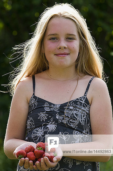 Girl holding strawberries and looking at camera