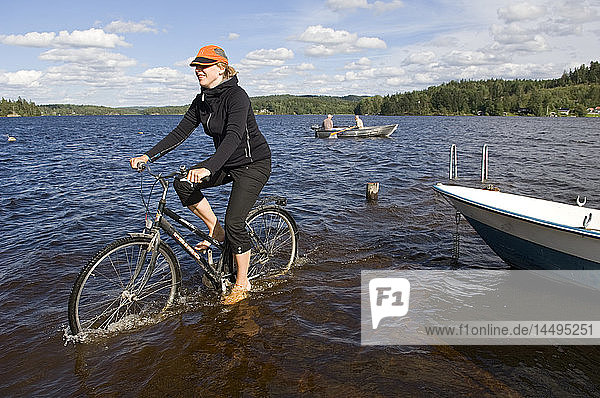 Eine Frau fährt auf einem Fahrrad im Wasser  Schweden.