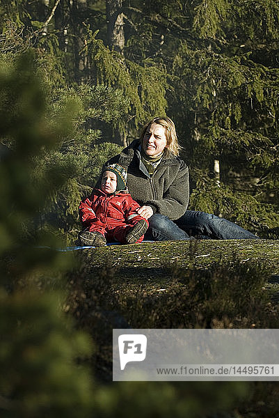 Mutter und Kind sitzen im Wald  Schweden.