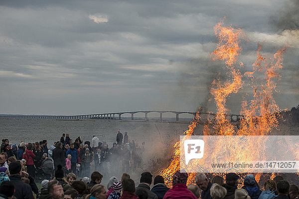 Menschen beobachten großes Lagerfeuer am Strand