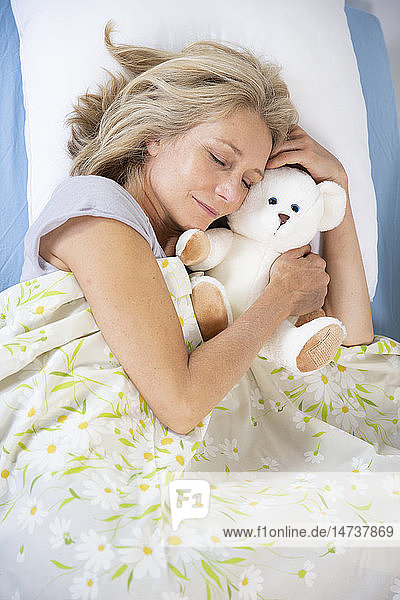 Eine Frau schläft mit einem Teddybär.