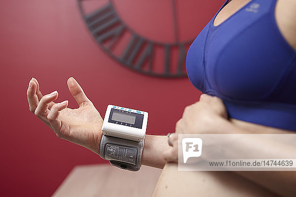Eine schwangere Frau misst ihren Blutdruck.