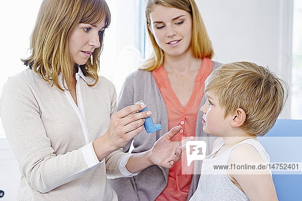Arzt informiert eine Mutter über die Verwendung eines Bronchodilatators.