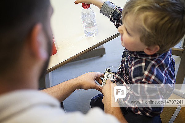 Reportage on the daily life of Oscar  a 3 and a half-year old boy who has type 1 diabetes. Oscar has a glucose sensor and insulin pump. He started nursery school this year. His parents had to train the school’s personnel in how to control and regulate his blood sugar levels throughout the day. A member of staff administers a bolus of insulin after a snack.