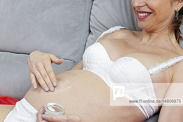 Schwangere Frau beim Eincremen ihres Bauches.
