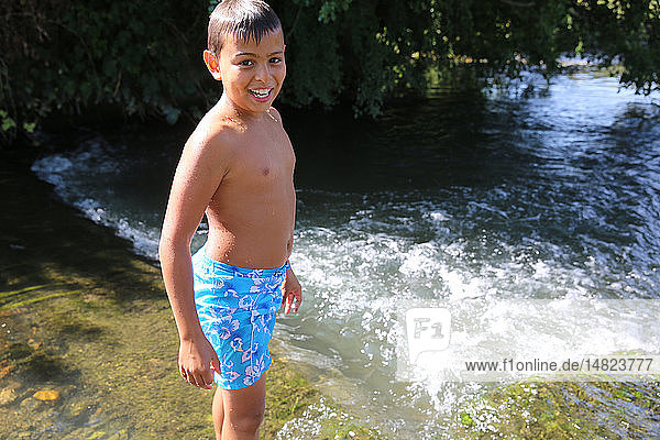 Junge watet in einem Fluss.