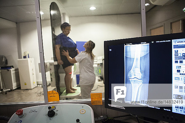 Reportage in einem Radiologiezentrum in Haute-Savoie  Frankreich. Ein Techniker führt eine Röntgenaufnahme des Knies eines Patienten mit beginnender Arthrose durch.