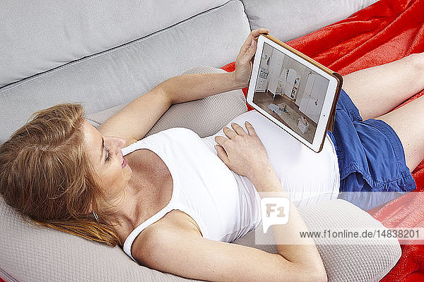 Pregnant woman using tablet computer.
