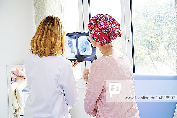 Ein Arzt erklärt einer Patientin das Ergebnis ihrer Röntgenaufnahme der Brust.