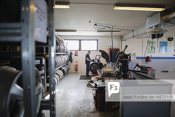 Man balancing the wheel in garage