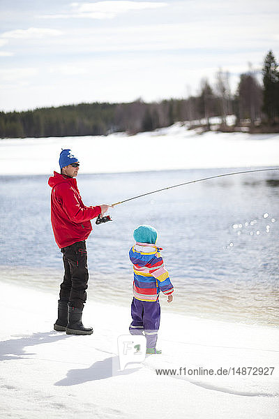 Vater mit Kind beim Fischen im Winter