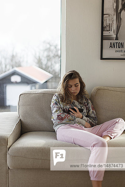 Teenager-Mädchen auf Sofa mit Handy