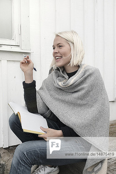 Young woman sitting on stairs with notebook