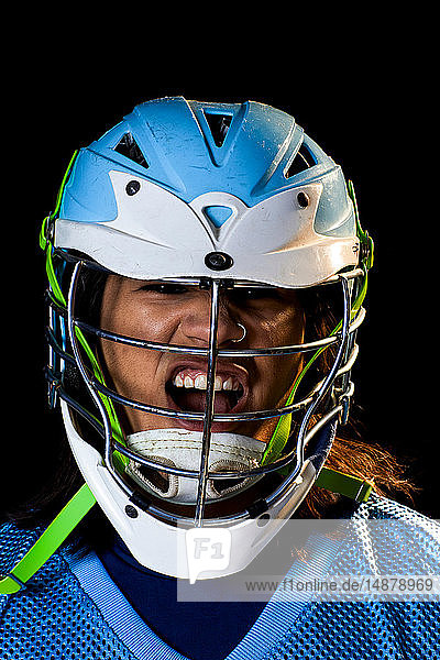 Junger männlicher Lacrosse-Spieler mit Lacrosse-Helm schreit  Nahaufnahme-Portrait vor schwarzem Hintergrund