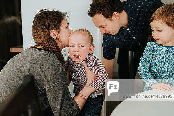 Paar mittlerer Erwachsener mit Kleinkind-Tochter und weinendem Baby-Sohn im Wohnzimmer