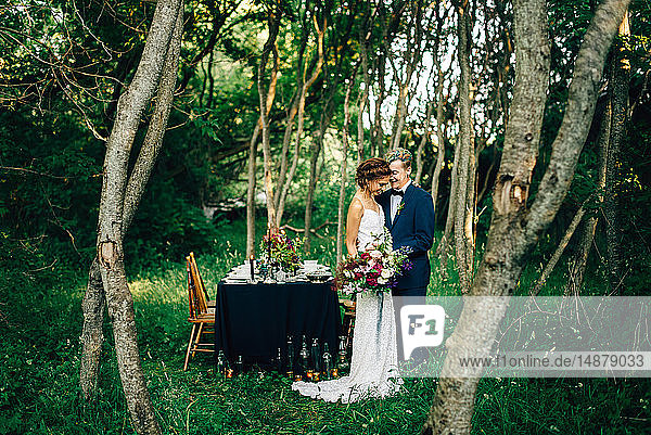 Romantic bride and groom by forest reception table