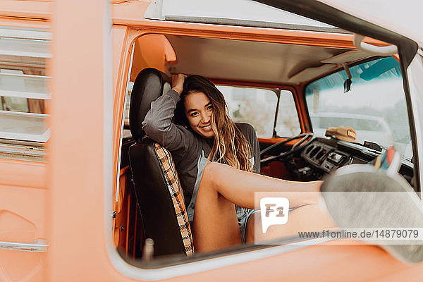 Young woman with feet through recreational vehicle window at beach  portrait  Jalama  California  USA