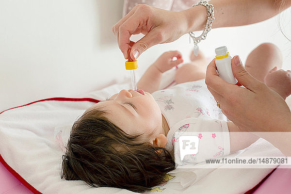 Mutter füttert Baby Mädchen Medizin im Bett