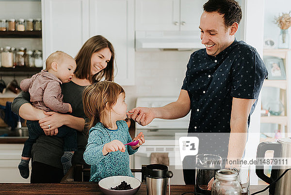 Paar mittlerer Erwachsener mit Kleinkind-Tochter und Baby-Sohn am Küchentisch