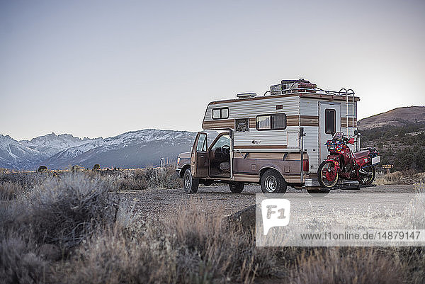 Wohnmobil mit Reisemotorrad dahinter in der Wüste geparkt  Sierra Nevada  Bishop  Kalifornien  USA