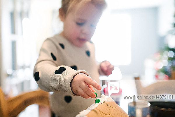 Kleinkind Mädchen schmückt Lebkuchenhaus zu Weihnachten
