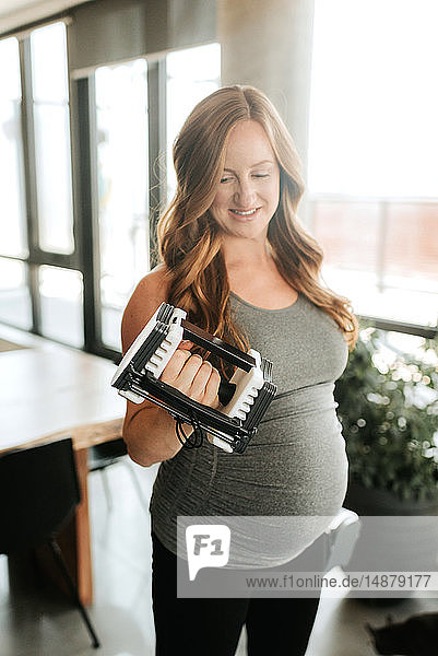 Pregnant woman using weights at home