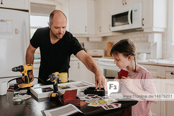 Girl helping father arrange cards into box in kitchen