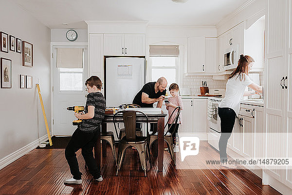 Family of four busy with chores in kitchen