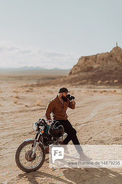 Motorradfahrer  der sein Getränk auf einem stationären Fahrrad genießt  Trona Pinnacles  Kalifornien  USA