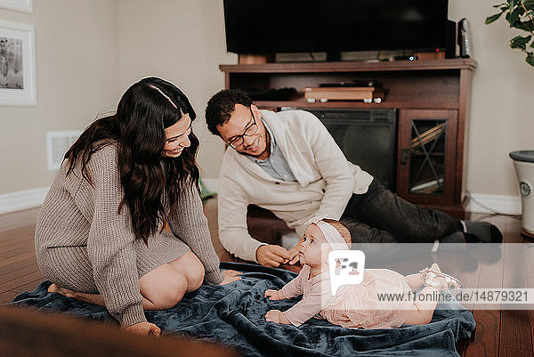 Couple playing with baby daughter in living room