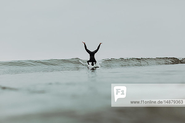 Junger männlicher Surfer macht Kopfstand auf dem Surfbrett in nebliger See  Ventura  Kalifornien  USA