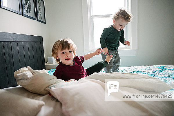 Brothers playing in bed