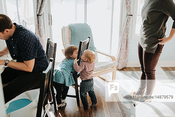 Kleiner Junge und kleine Schwester spielen im Wohnzimmer mit Mutter und Vater