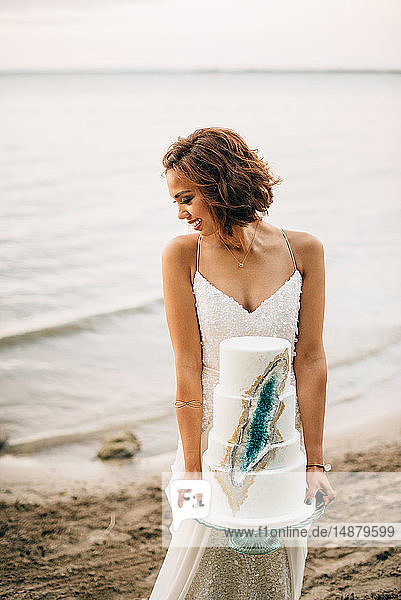 Young bride carrying wedding cake on lakeside  Lake Ontario  Toronto  Canada