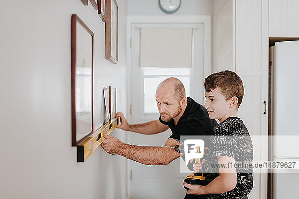 Father teaching son drill wall for picture frames