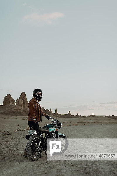 Motorradfahrer neben stationärem Fahrrad in der Wüste  Trona Pinnacles  Kalifornien  USA