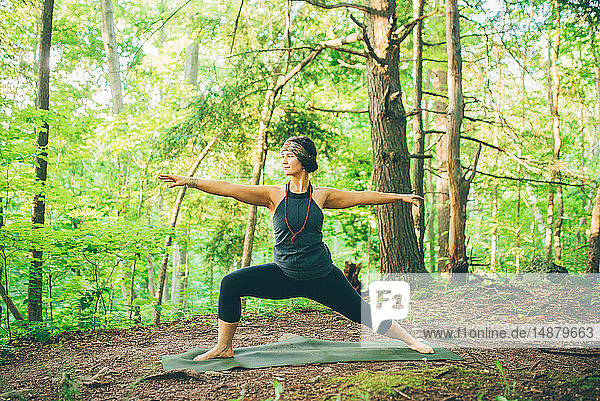 Woman doing warrior pose in forest