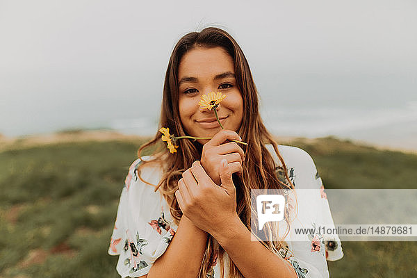 Junge Frau hält an der Küste Wildblumen vor dem Gesicht  Porträt  Jalama  Kalifornien  USA