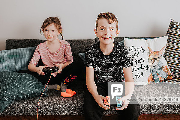 Children playing video game on couch
