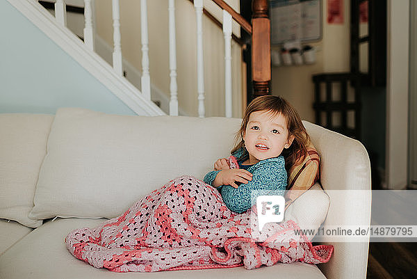 Weibliches Kleinkind auf Sofa mit Decke  Portrait