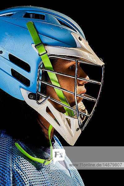 Junger männlicher Lacrosse-Spieler mit Lacrosse-Helm  Nahaufnahme-Portrait vor schwarzem Hintergrund