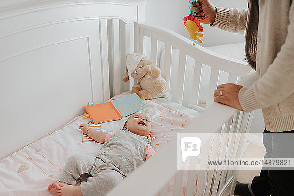 Vater bringt Baby-Tochter im Kinderbettchen ins Bett