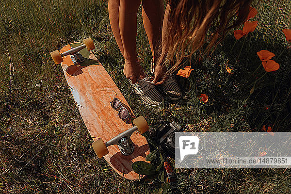 Junge Skateboardfahrerin beim Schnürsenkelbinden im Gras  Jalama  Kalifornien  USA
