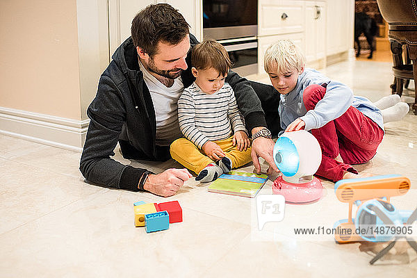 Father and sons playing with toys on floor