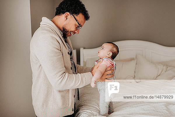 Father talking face to face with baby daughter