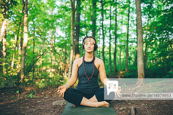 Woman doing enlightened pose in forest