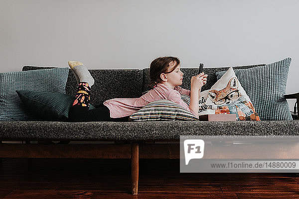 Girl playing with smartphone on couch