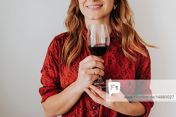 Frau hält ein Glas Wein  weißer Hintergrund